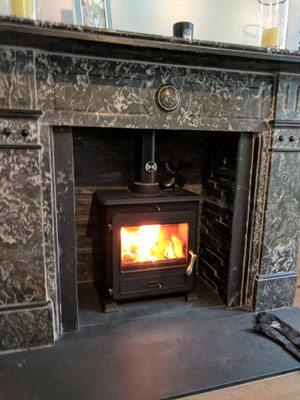 Lit log burner in Victorian black/white marble fire surround. Eco black slate panels
