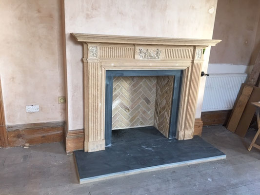 Installed fireplace chamber in buff brick. Herringbone. Sandstone fire surround. Grey slate hearth