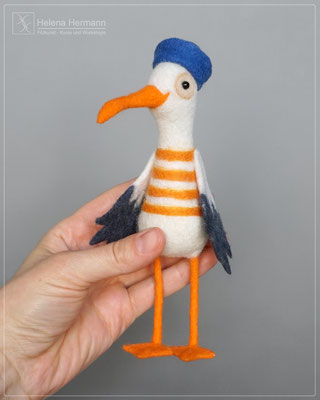 Handgefilzte Möwe „Moin-Möwe“ wird in einer Hand gehalten und zeigt so ihre Größe.