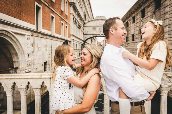 Close-up of a child's genuine laughter during a Venice family photoshoot, with the blurred background of a Venetian canal emphasizing focus on emotion.