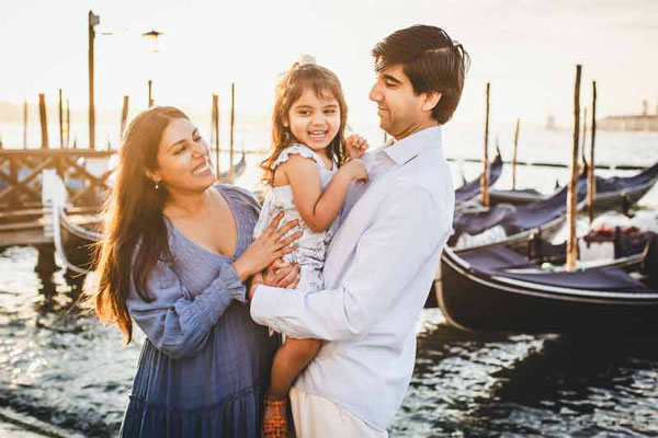 A candid shot of a family walking hand-in-hand over a small, uncrowded bridge in Venice, showcasing natural movement and connection.