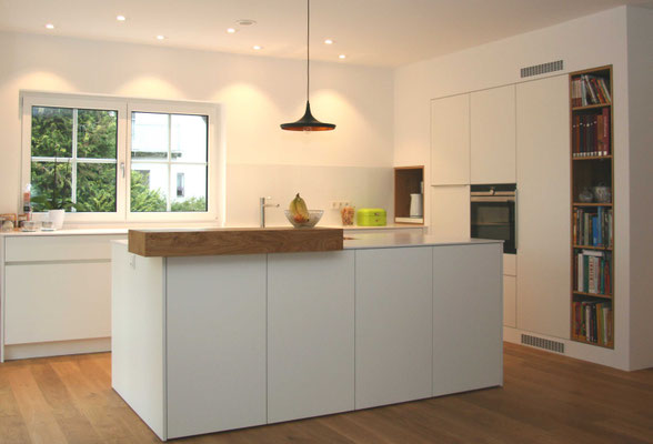 Weiße Küche mit Kochinsel und Bücherregal in Holz