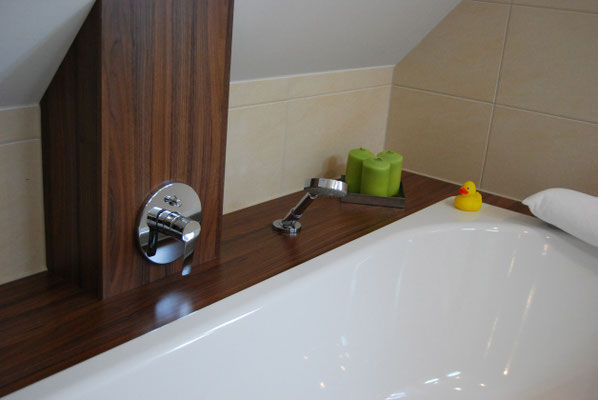 Maßgefertigte Badewanne aus dunklem Holz in Dachschräge