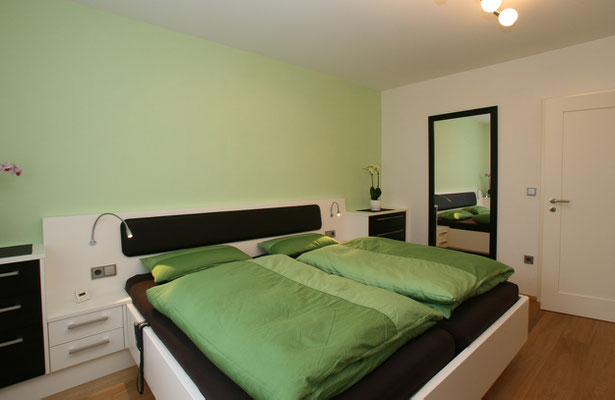 Schwarz-weißes Doppelbett in einem grünem Schlafzimmer