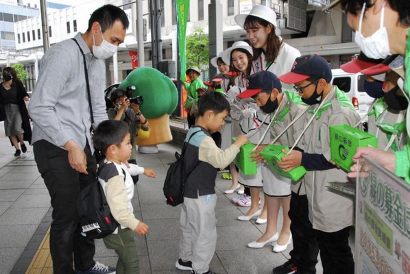 おこずかいを募金する親子連れ