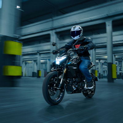 CFMOTO 125NK fahrend in Industriehalle mit Licht