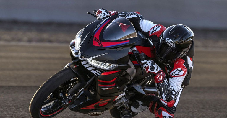 Aprilia RS 457- Ansicht von links mit Fahrer in einer Rennstreckenkurve und Schräglage