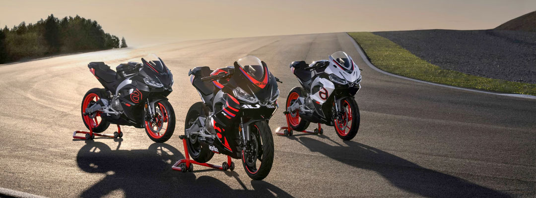 Aprilia RS 457- 3 Modellfarben nebeneinander aufgebockt auf einer Rennstrecke im Sonnenuntergang