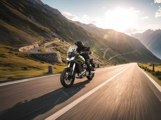 Moto Guzzi Stelvio PFF RAS in Verde Hiking fahrend auf Bergstrasse mit Serpentinen im Hintergrund