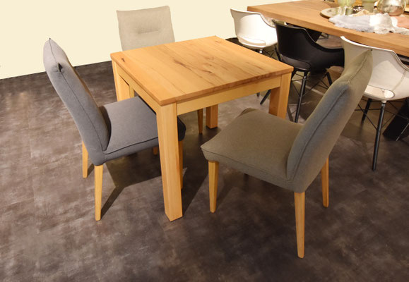 Kleiner, heller Holztisch mit vier Esszimmerstühlen in Grau und Beige.