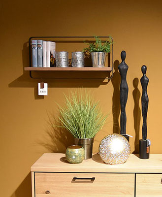 Eine Regal mit Dekoration, darunter eine Holzkommode Statuen, Pflanze und Lampe.