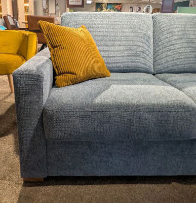 Blaues Sofa mit senfgelbem Kissen in modernem Wohnzimmerambiente.