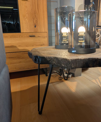 Detailansicht eines Couchtischs mit Baumscheibenplatte und Haarnadelbeinen, darauf zwei Glaslampen.