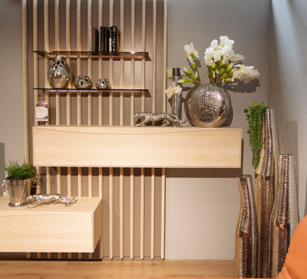 Holz-Sideboard, umgeben von silbernen Dekorationen und einer vertikalen Lamellen-Holzwand.