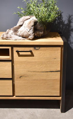 Nahaufnahme heller Eichenschrank mit schwarzem Metallrahmen und dunkelbrauner Fell-Deko.