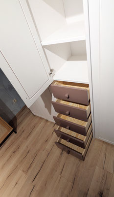 Offener weißer Schrank mit Regalboden und fünf ausgezogenen Rosé-Schubladen.