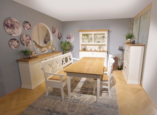 Esszimmer mit Holztisch, weißer Bank und Stühlen, weißem Geschirrschrank und Sideboard.