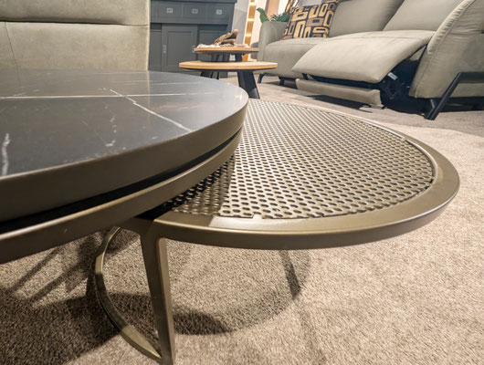 Zwei runde Couchtische, mit schwarzer Marmorplatte und mit gelochtem Metall, auf beigem Teppich.