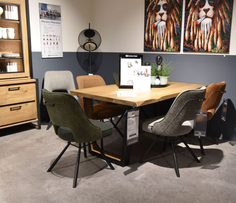 Esszimmer-Set in hellem Holz mit Mix aus hellbraunem Leder- und grauen Stoffstühlen auf grauem Teppich.