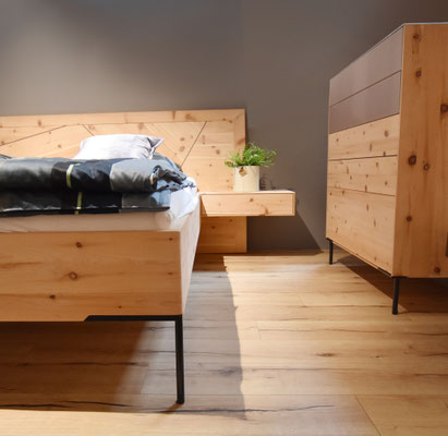 Holzschlafzimmer mit einem Nachttisch, auf dem eine kleine Pflanze steht.