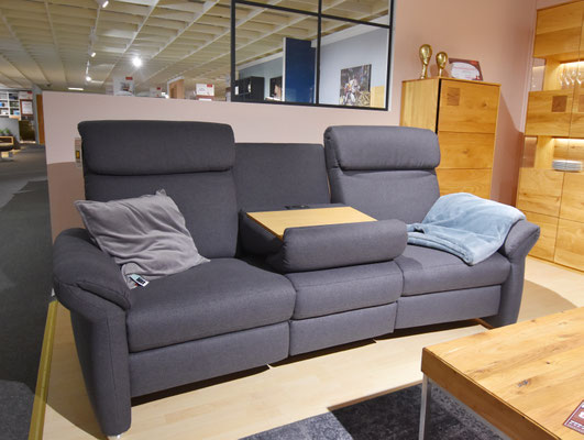 Graues 2er-Sofa mit Entspannungsfunktion und einem Kabelfernbedienungspad auf der Sitzfläche.