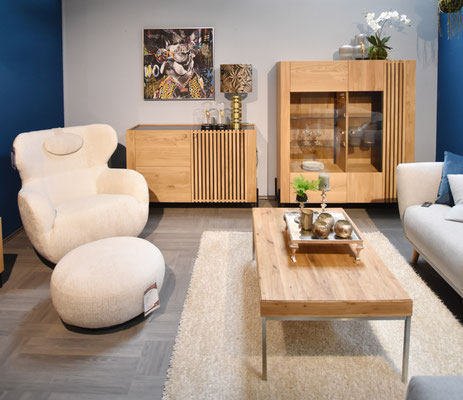 Helles Wohnzimmer mit Sessel, Schränken. Couchtisch und Sofa.