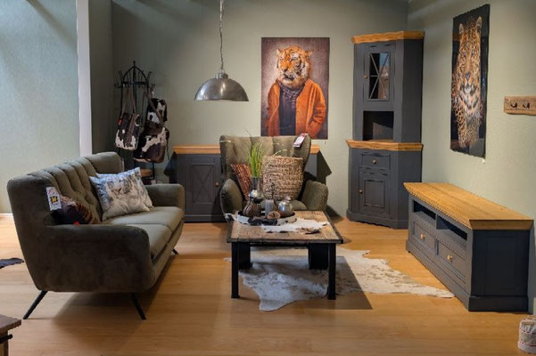 Ein Wohnzimmer mit dunkelgrauen Möbeln mit Holzoberflächen, ein Sofa, Sessel und Couchtisch.
