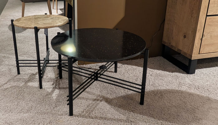Zwei runde Beistelltische mit schwarzen Metallgestellen und unterschiedlichen Tischplatten.