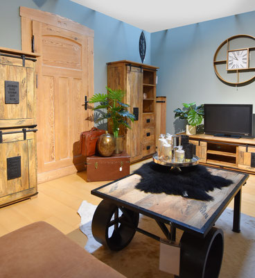 Rustikales Wohnzimmer mit hellblauen Wänden, Möbeln aus Massivholz und einem Couchtisch auf Rollen.