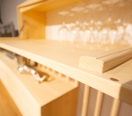 Unscharfe Detailansicht einer aufgeklappten Holzbar mit Weingläsern.