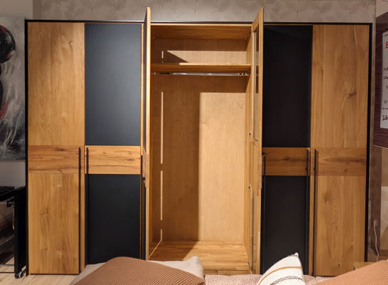Großer Kleiderschrank aus Holz und schwarzem Dekor mit geöffneter Mitteltür.