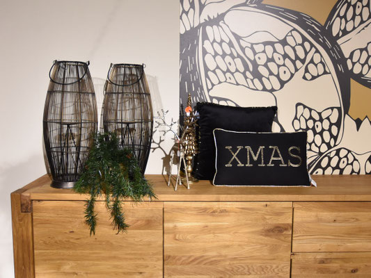 Weihnachtsdekoration auf Kommode: zwei schwarze Drahtkörbe, Rentier-Figuren und ein "XMAS"-Kissen.