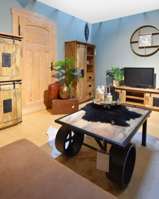  Wohnzimmer mit hellblauen Wänden, Holztür, Schränken und einem rollenden Couchtisch mit Felltuch.