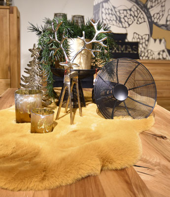 Ein Reh-Teelichthalter und Windlichter auf einer gelben Kunstfell-Unterlage, Weihnachtsdekoration.
