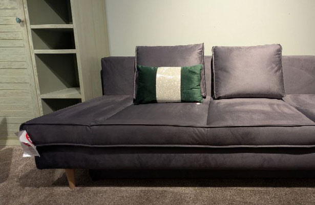 Dunkelgraues Samt-Schlafsofa mit zwei großen und einem grün-weiß gestreiften Zierkissen.