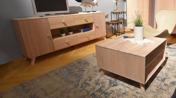Schlichtes, helles Holz-Sideboard und Couchtisch mit geriffelten Fronten in einem Wohnzimmer.