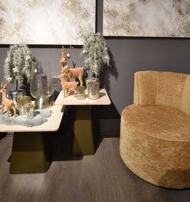 Weihnachtsdekoration mit goldbraunem Sessel, Rentierfiguren und schneebedeckten Kunstbäumen.