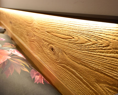 Nahaufnahme einer beleuchteten Holzkante und einem floralen Kissenbezug.