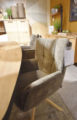 Zwei weiche, olivgrüne Sessel in einem modernen Raum mit einem Holztisch und einem Teppich.