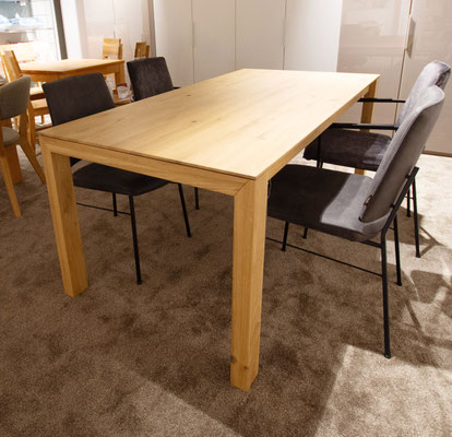 Rechteckiger Holztisch mit vier grauen Stühlen.