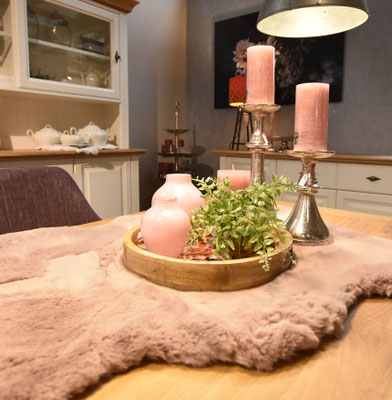 Tischdekoration mit Pelzläufer, Tablett mit rosa Vasen, grüner Pflanze und silbernen Kerzenständern.