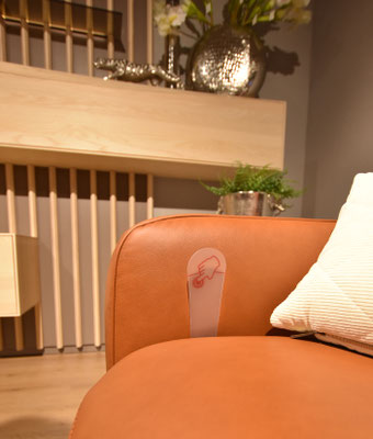 Ein braunes Ledersofa mit Aufkleber für Touchpoint und einem weißen Kissen.