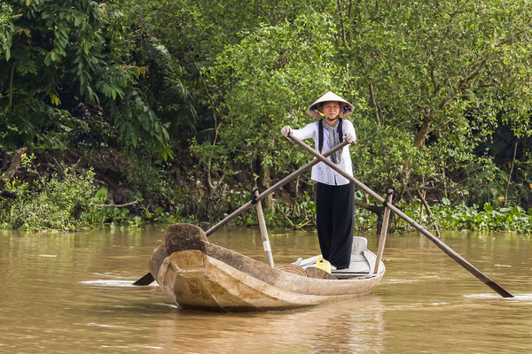 Eine Vietnamesin ruder auf einem Holzboot in einem Seitenkanal des Mekong, Mekong-Delta, Vietnam, Asien