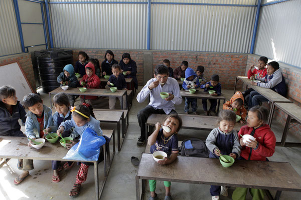 Die Kinder mit Lehrer Mr. Luitel am Essen