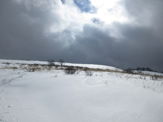 穴の空いた雲間からの光で輝く雪面