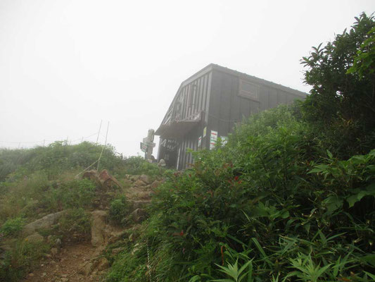 ガスのなかの三国小屋　小屋前広場の脇は巨大なスラブになっていて急崖です