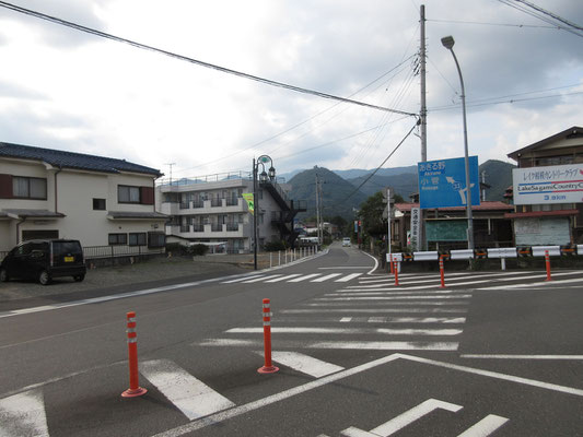 バスの本数が少ないので「新井」という町の交差点停留所まで歩いてようやく到着　道の向こうには、登った要害山が「お疲れさま」と見送ってくれている