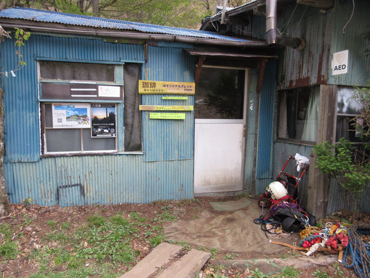 朝、出発前の丸川荘　入り口のギア数々は、小屋にかぶる樹木伐採の為に登って来ている“特殊技能”を持つイケダさんの装備