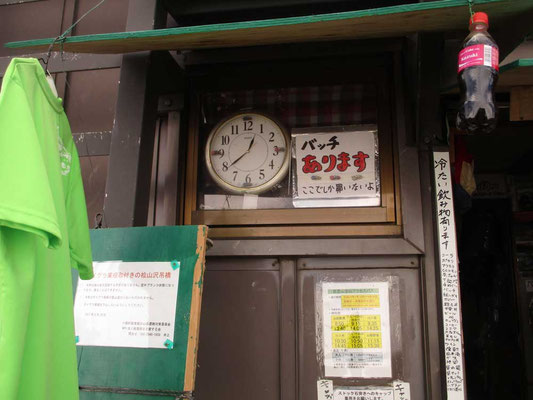 本山小屋の壁にはまっている時計 そしてバッチなどの宣伝看板