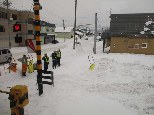 宗谷本線車窓からある踏切通過のショット　除雪作業の人たちが手を上げて列車通過の安全確認をしています